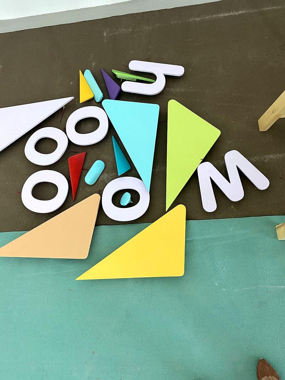 Pieces of the woo-hoo! logo laid out on the floor before mounting.