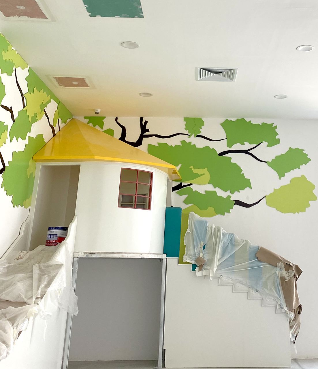 The treehouse and leaf mural nearly finished, with ceiling panels still open.