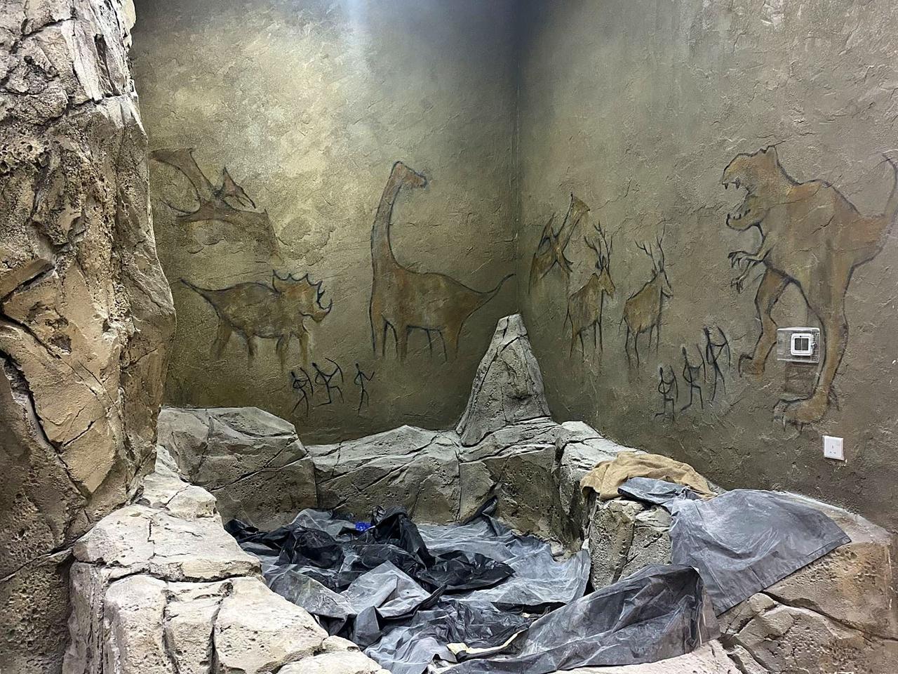 A finished cave room painted with dinosaurs and early hunters, awaiting final clean-up.