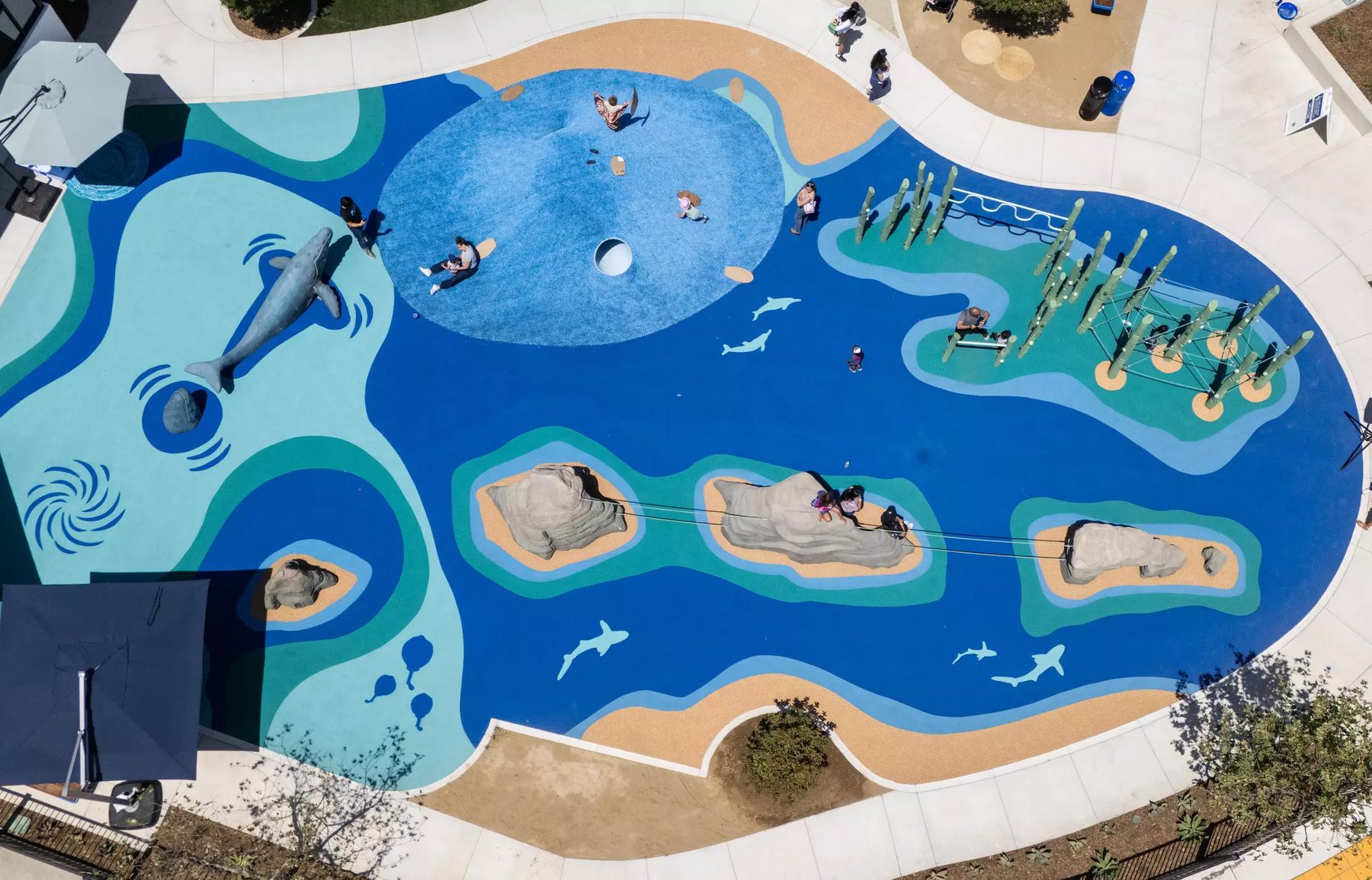 Aerial view of kidSTREAM's blue ocean-themed outdoor water-play area shaped like the Channel Islands.