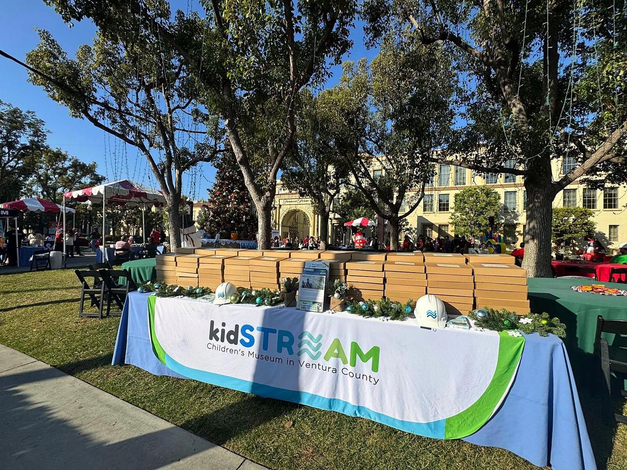 A kidSTREAM table stacked with STREAM kits at a holiday community event.