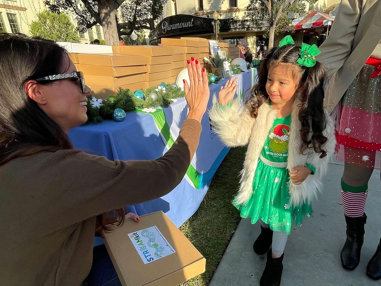 A kidSTREAM team member high-fiving a young girl while handing out STREAM kits.