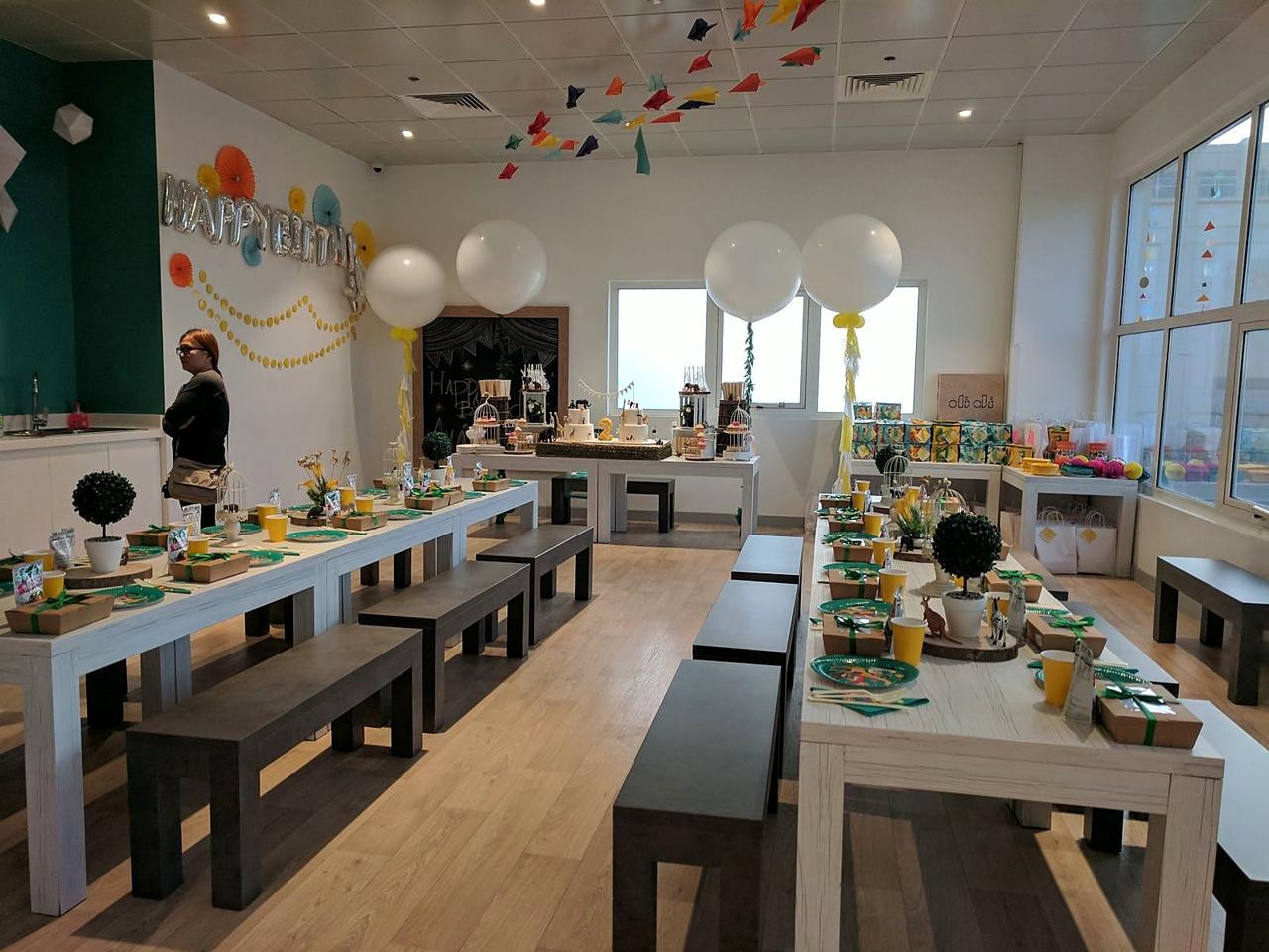 A birthday party room styled with giant balloons, paper planes and a safari table setting.